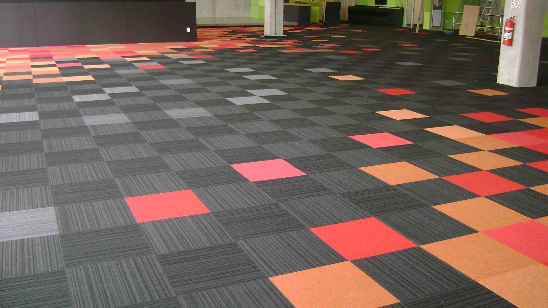 home-img A large open office space with a colorful patterned floor made of black, gray, red, and orange carpet tiles.